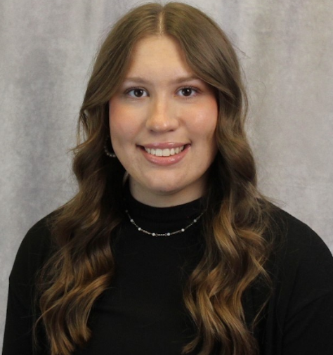 Emily in a black dress shirt and cardigan